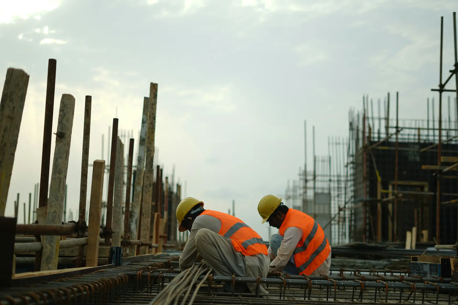 Deux ouvriers ferraillent une dalle sur un chantier.