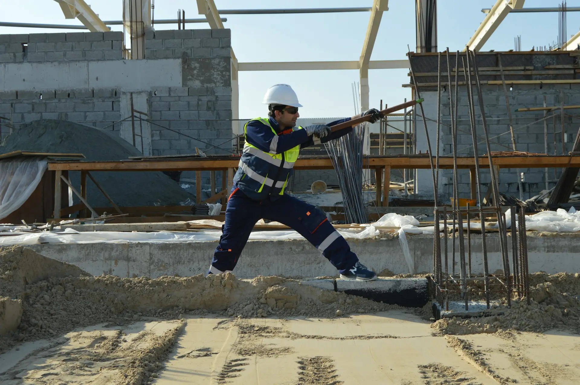 Ouvrier sur un chantier de gros œuvre, entre les fers en attente.